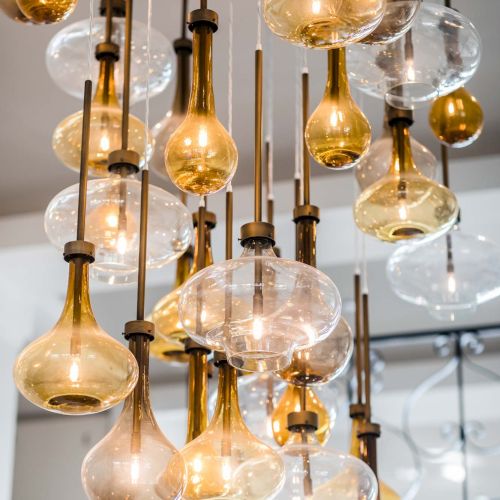 A cluster of hanging glass bulb lights with warm amber glow, suspended by dark cords and metal rods. Great interior lighting.