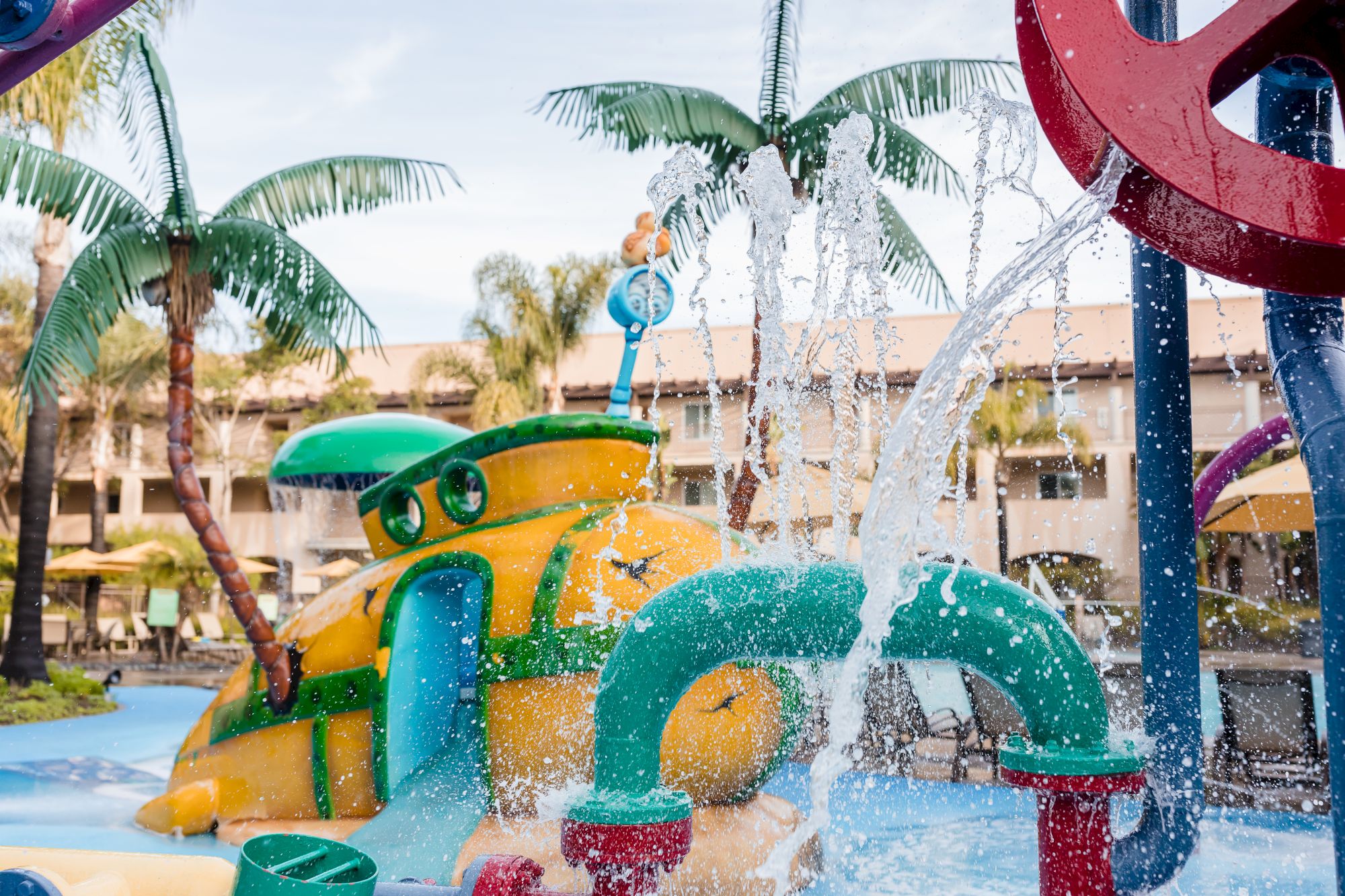 A backyard water park splash playscape with colorful slides and jets spraying water into the air.